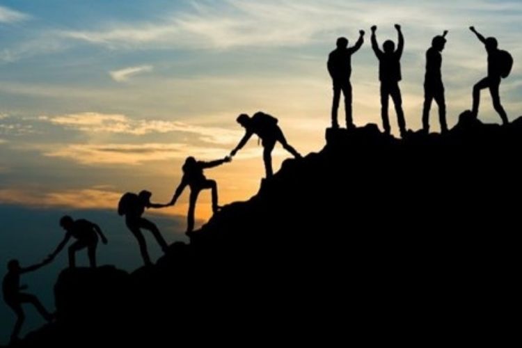 team helping each other climb a mountain